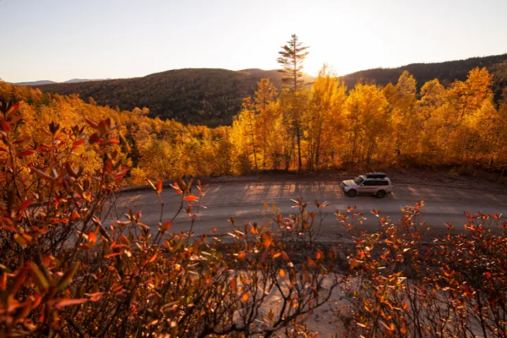 Vista de una carretera de montaña en otoño con un 4x4
