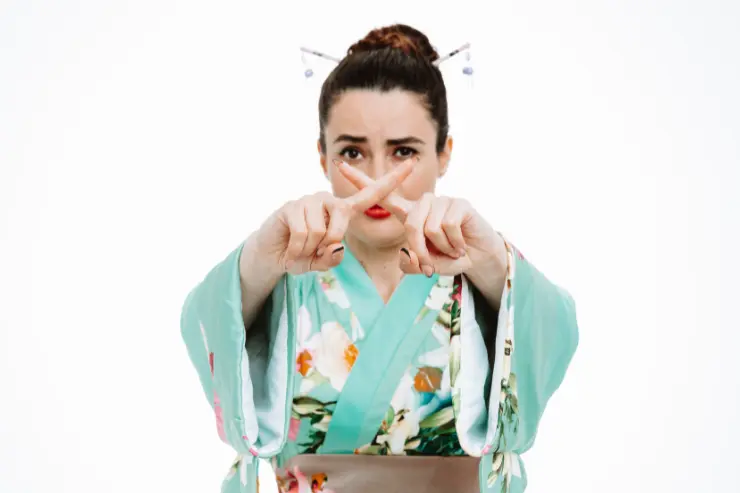 Mujer japonesa haciendo una cruz con sus dedos