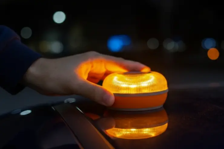 Una mano sujeta una baliza v-16 en el techo del coche