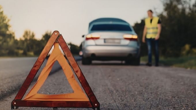 Persona con el coche estropeado y con los triángulos de seguridad